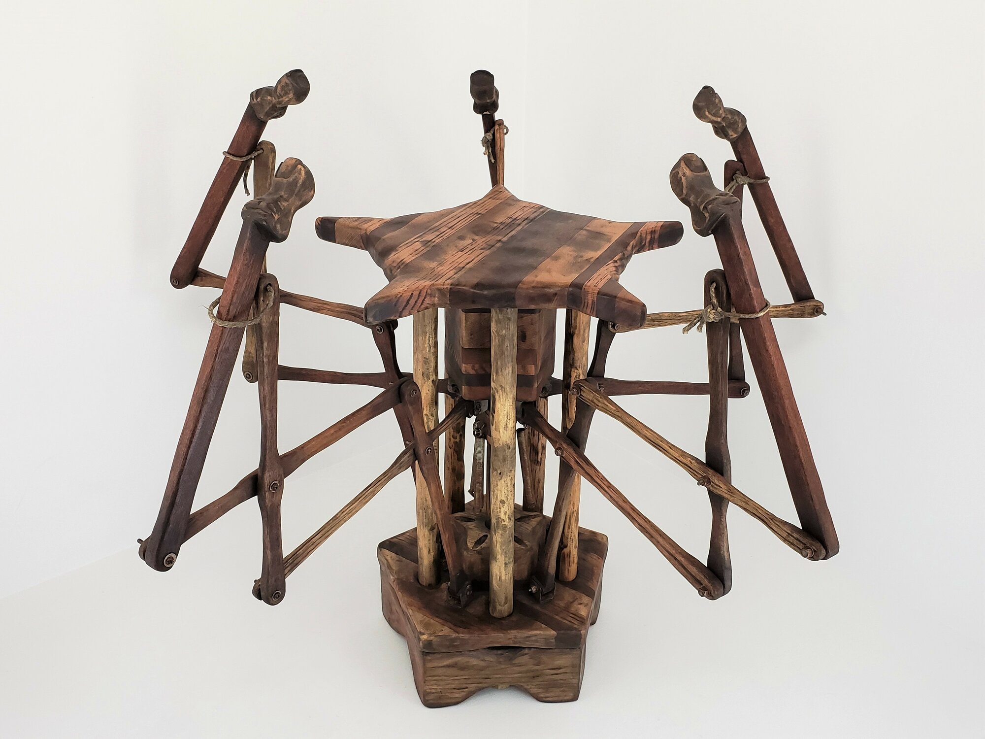 This stool points towards an occupant when the weight of a person rests on the seat. The five finger mechanisms extend and rise from beneath the seat when depressed. Once weight is released, springs pull the fingers down to their starting position and the